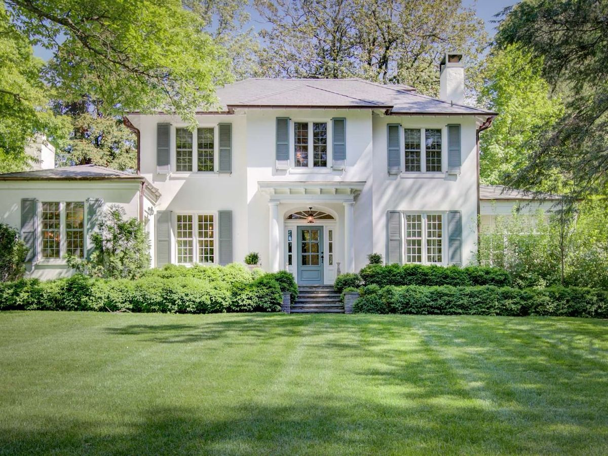 A cozy and elegant living room filled with warm wood ceilings, a large leather sectional, and wall-to-wall windows. This mid-century modern retreat is designed for comfort and surrounded by forest views.