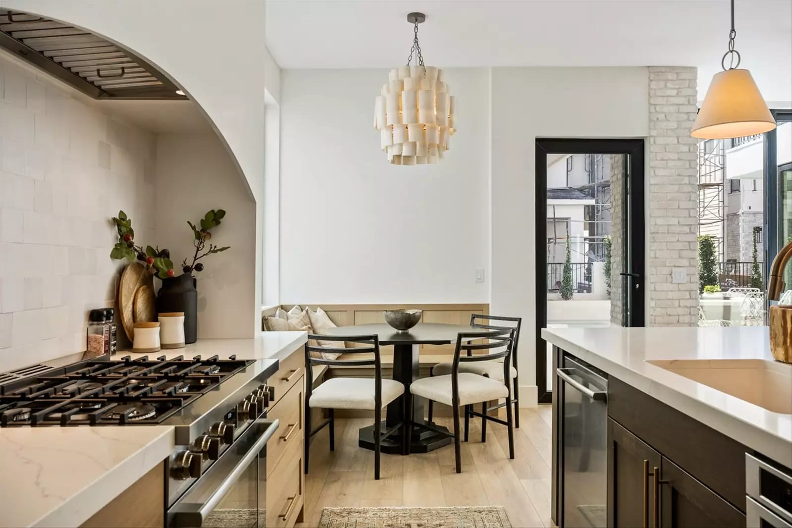 Cozy kitchen nook with a built-in bench, round dining table, and modern light fixture beside a bright, open cooking space.