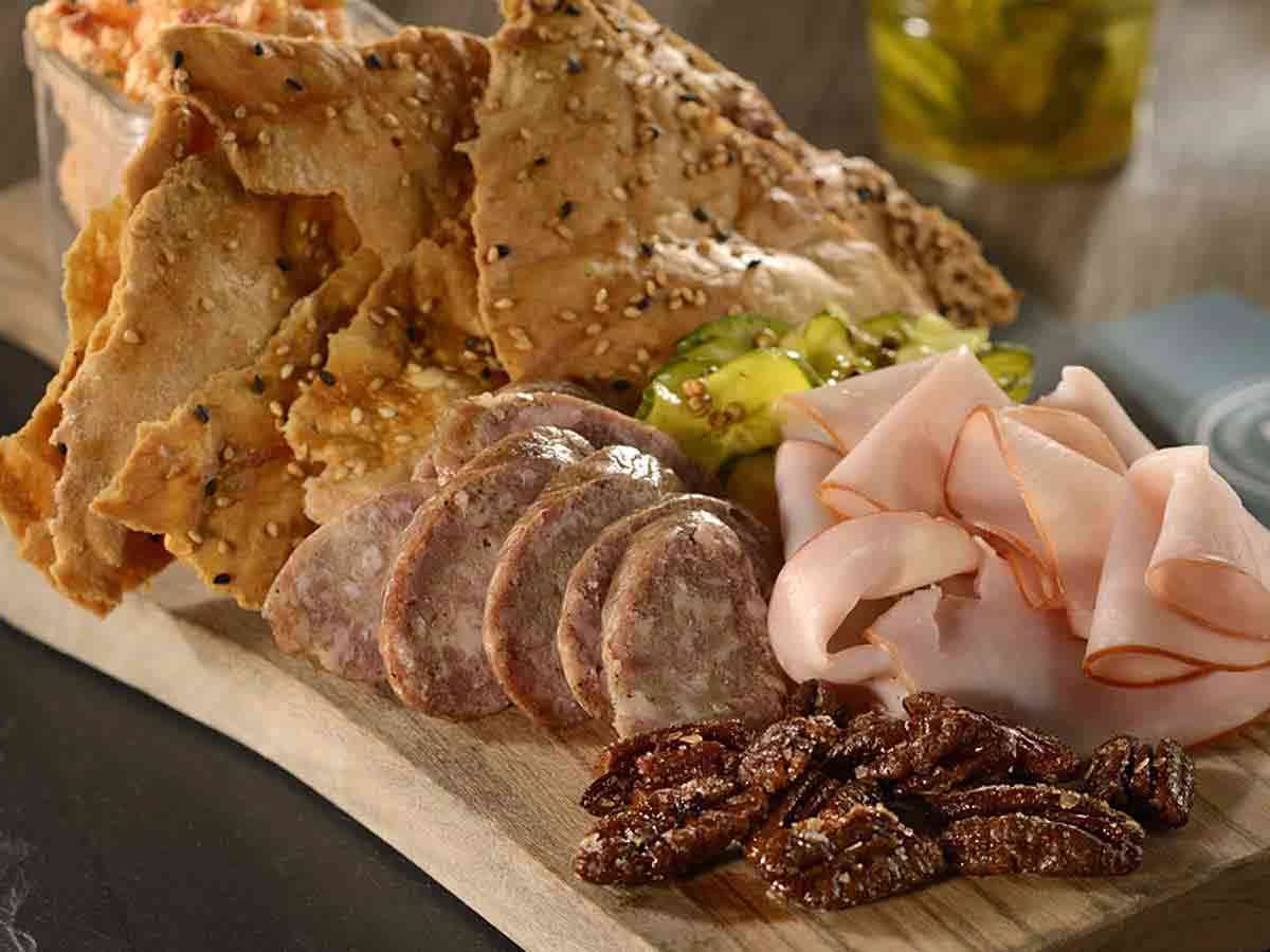 Charcuterie board at Homecomin’ Kitchen featuring smoked meats, artisan crackers, pickles, and candied pecans. A rustic Southern starter full of flavor.
