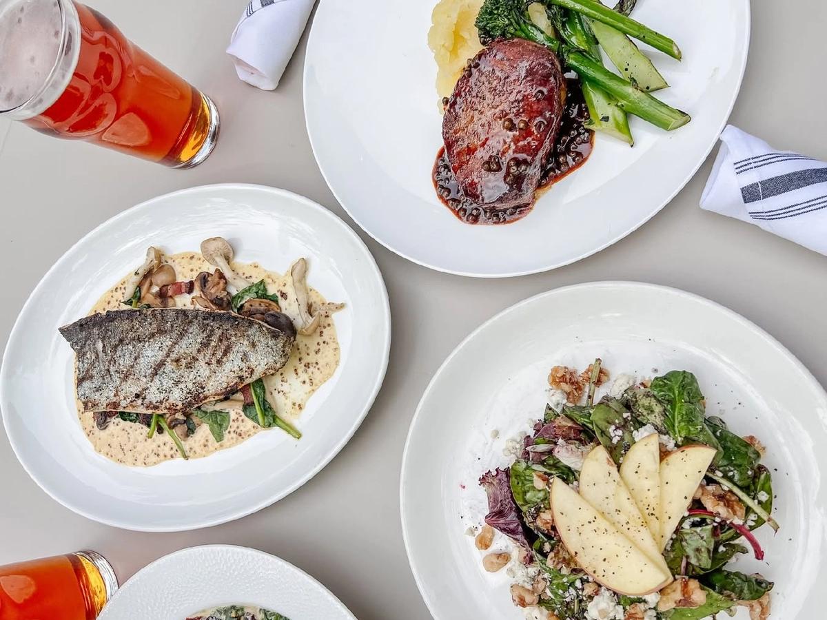 Elegant fine dining spread featuring seared fish, fresh salads, and a perfectly cooked steak with seasonal vegetables, paired with craft beer.