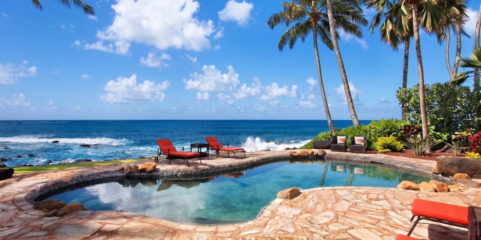 A tropical vacation rental with a private oceanfront pool and palm trees is paired with the headline “Airbnb Is Changing Its Fees on September 15.” The image introduces a travel guide explaining what Airbnb’s fee changes could mean for travelers planning their next vacation.
