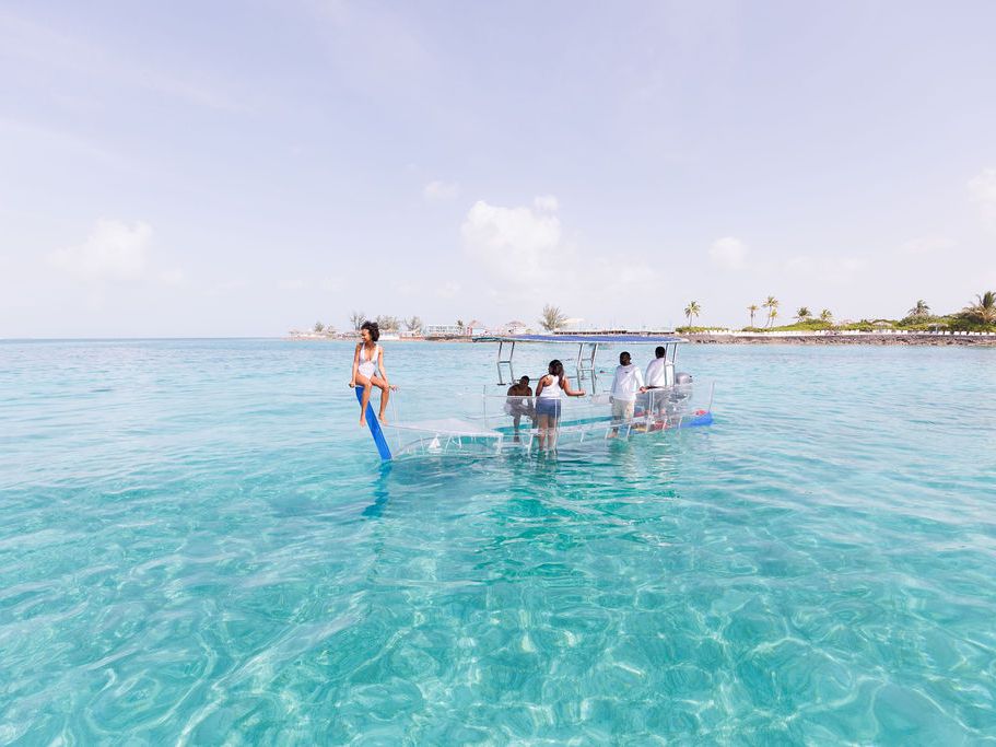 A group of friends enjoys a glass-bottom boat ride over crystal-clear turquoise waters, revealing the marine life below. It’s the perfect way to experience the Bahamas’ stunning underwater world without getting wet.