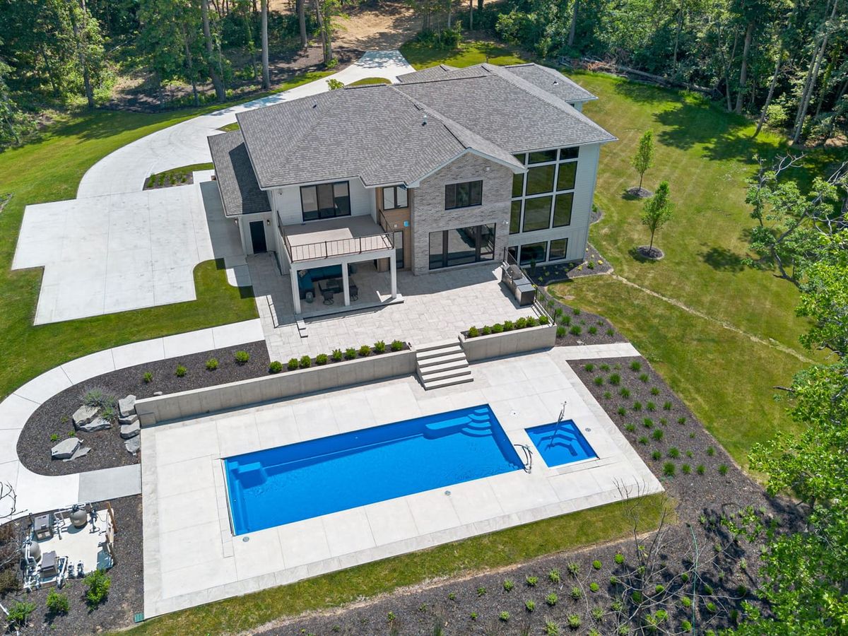 Expansive luxury home with a private pool, sun loungers, hot tub, and fire pit, surrounded by trees and open lawn, perfect for family fun and tail-wagging adventures. Pets will love the room to explore while guests enjoy lakeside views and fireside chats under the stars.