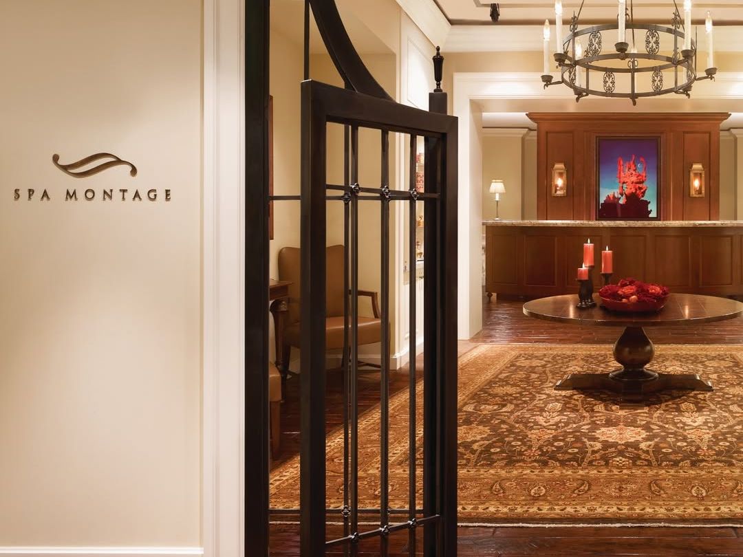 The luxurious entry to Spa Montage Deer Valley featuring warm lighting, elegant iron gates, and rich wooden floors. A chandelier and serene ambiance set the tone for a relaxing wellness retreat.
