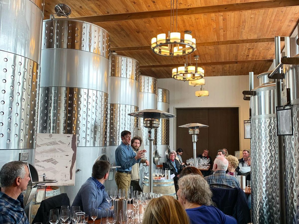 Visitors take part in a wine tasting at Hermann J. Wiemer Vineyard, seated among large stainless steel tanks. The space highlights the vineyard’s focus on quality and winemaking tradition.