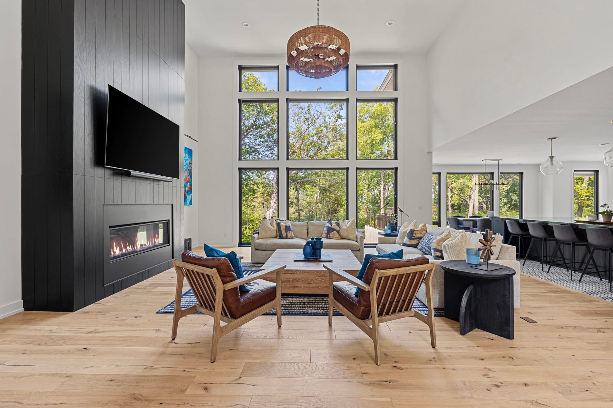 Modern vacation home living room with fireplace, large windows, and open-concept design