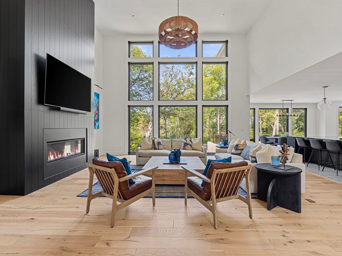 Modern vacation home living room with fireplace, large windows, and open-concept design