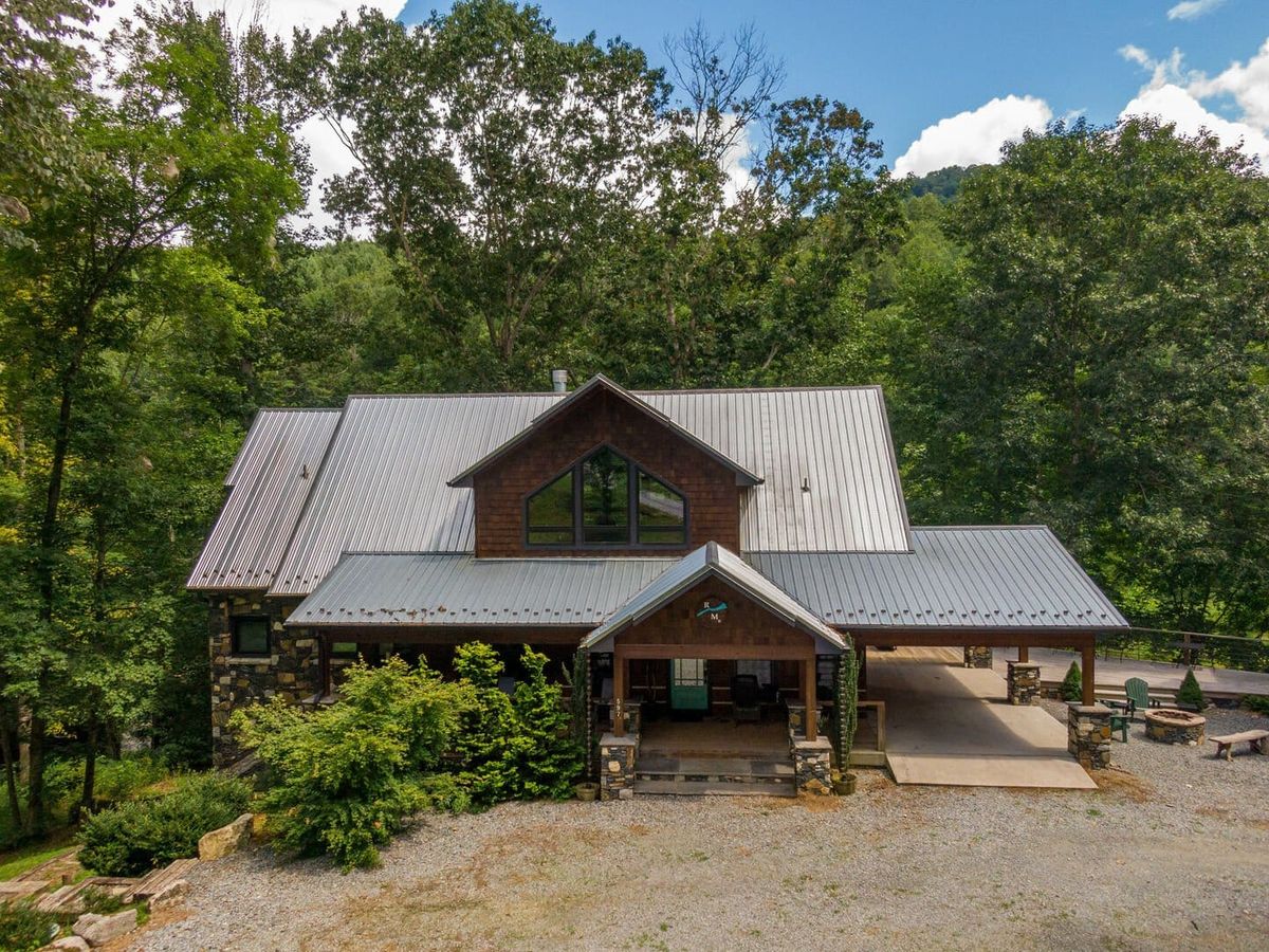A River Mist Too is a rustic cabin surrounded by lush trees, offering privacy and charm. Its stone accents and wide front porch invite families to relax and enjoy the outdoors.