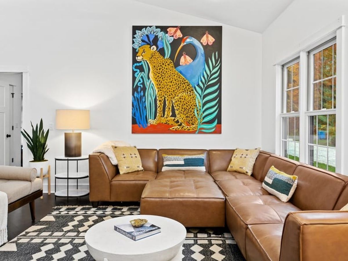 Stylish living room with a leather sectional, bold cheetah artwork, and cozy lighting that’s made for curling up after outdoor adventures. With room for the whole crew, furry ones included this space feels both playful and peaceful.