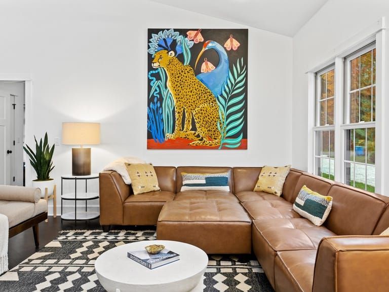 Stylish living room with a leather sectional, bold cheetah artwork, and cozy lighting that’s made for curling up after outdoor adventures. With room for the whole crew, furry ones included this space feels both playful and peaceful.