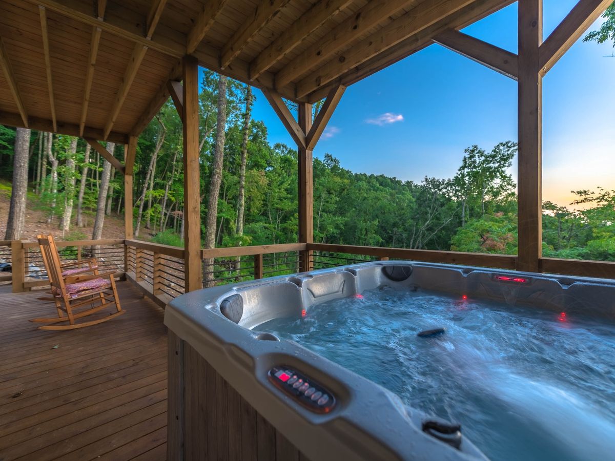 Private hot tub on balcony next to rocking chair with mountain views and blue skies