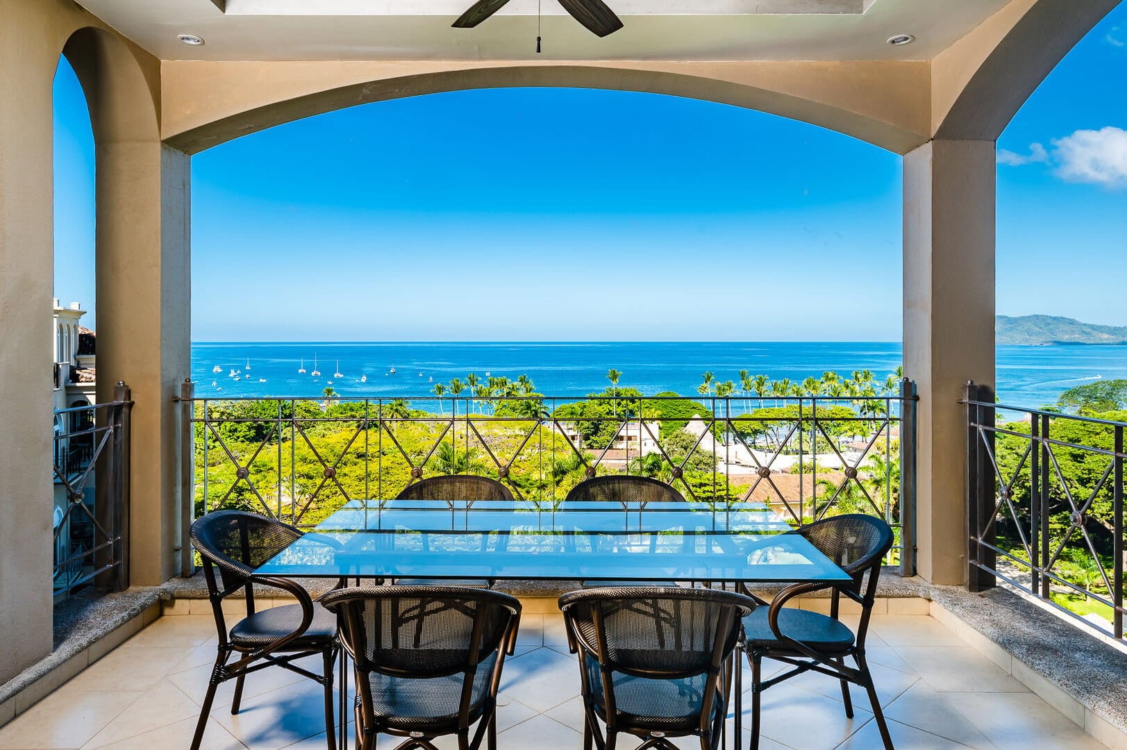 This covered balcony in Tamarindo overlooks lush greenery and the deep blue ocean. Guests can enjoy outdoor dining while watching boats drift across the horizon. Matapalo Penthouse 701 offers comfort with beautiful coastal views.
