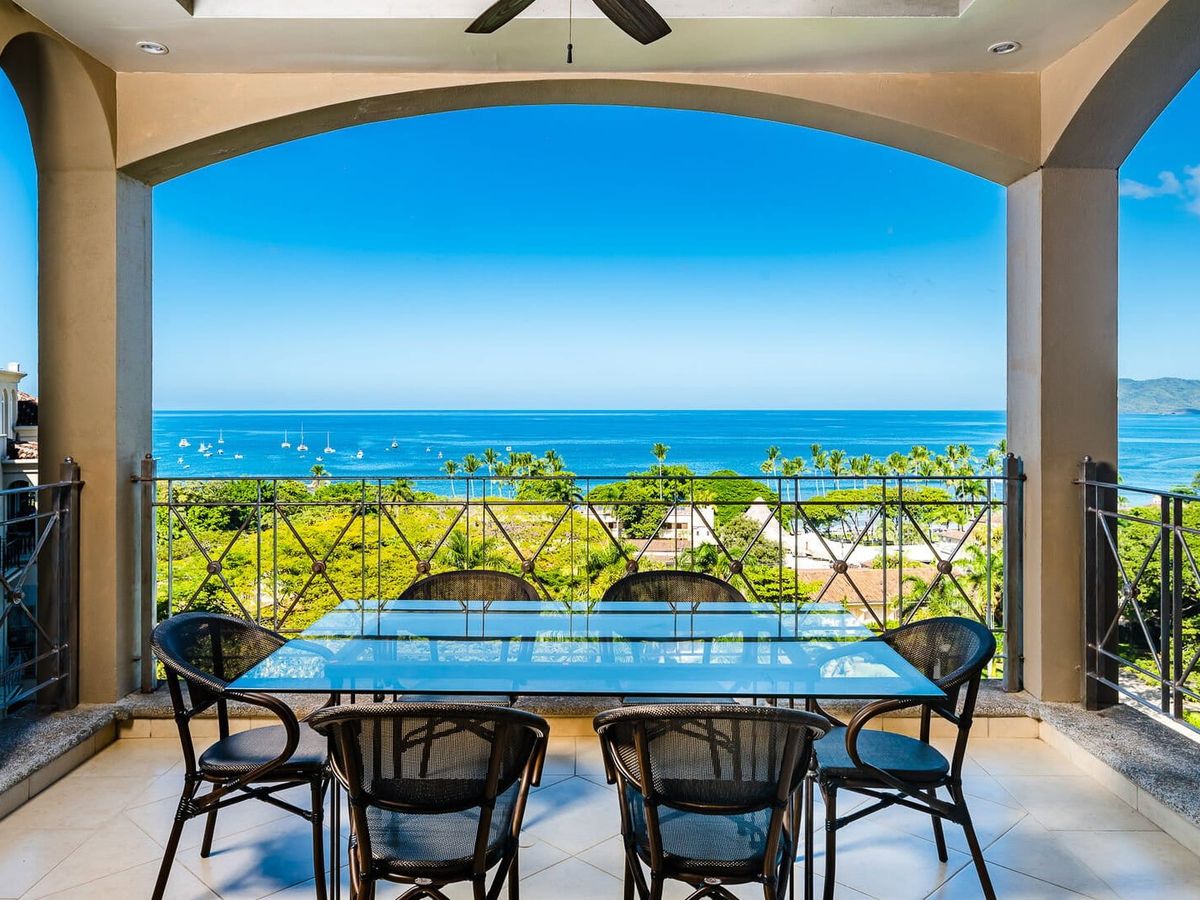 This covered balcony in Tamarindo overlooks lush greenery and the deep blue ocean. Guests can enjoy outdoor dining while watching boats drift across the horizon. Matapalo Penthouse 701 offers comfort with beautiful coastal views.