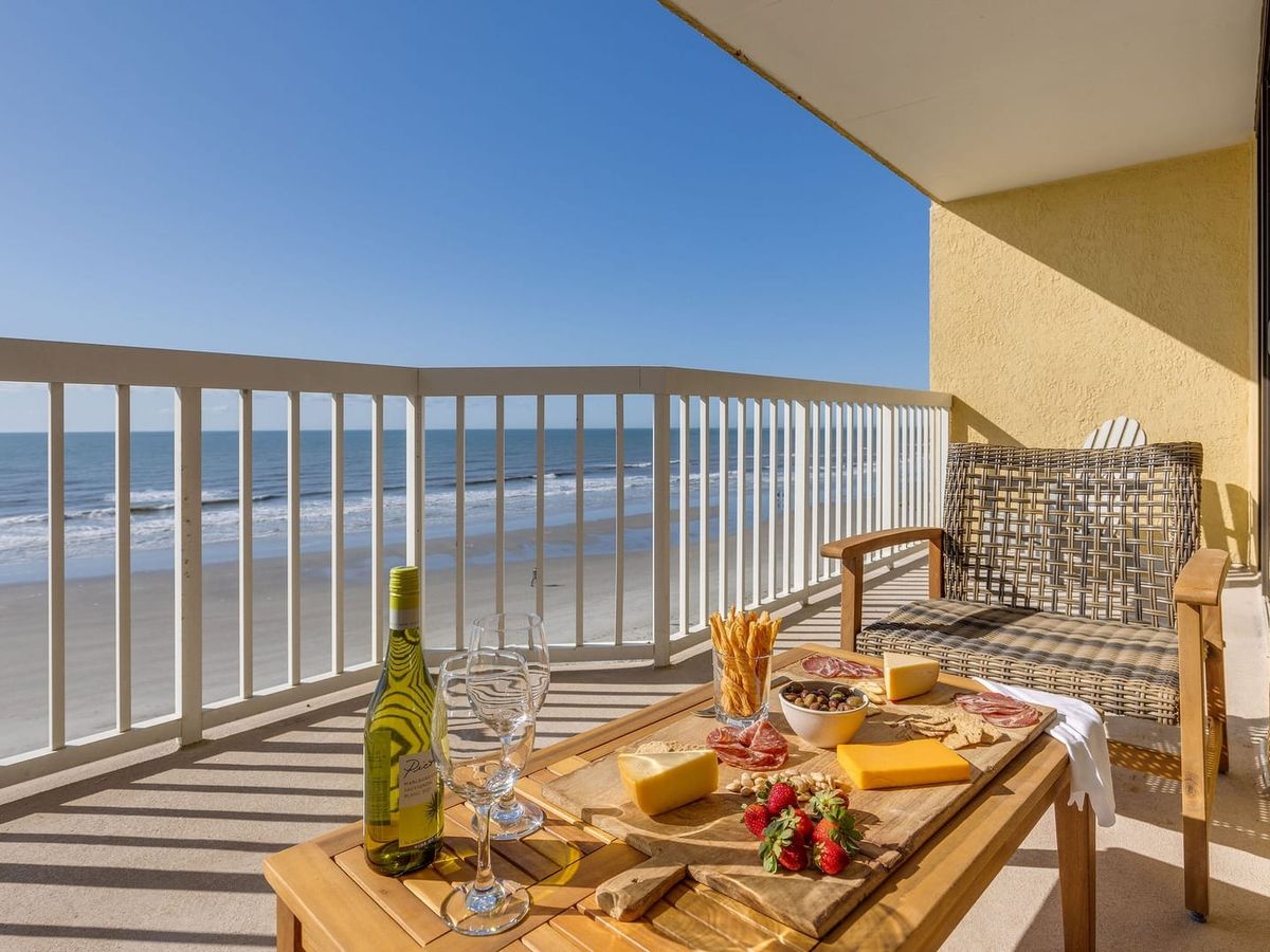 Private oceanfront balcony with lounge seating, wine glasses, and a snack board overlooking the shoreline. It’s an easy place to slow down, enjoy the sea breeze, and watch the waves roll in at Folly Beach.