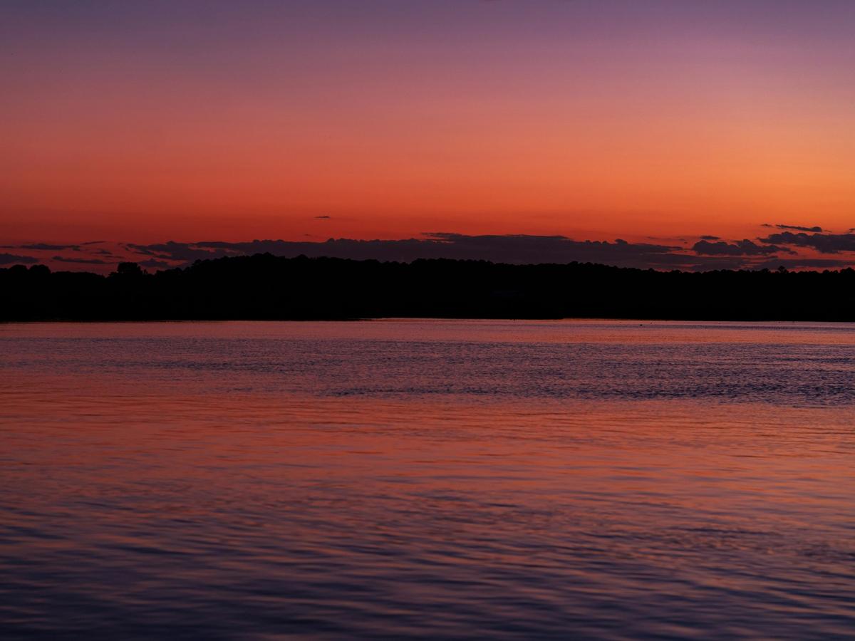 Vibrant sunset over the Chincoteague Bay in Virginia, with deep orange and purple hues reflecting off the calm coastal waters