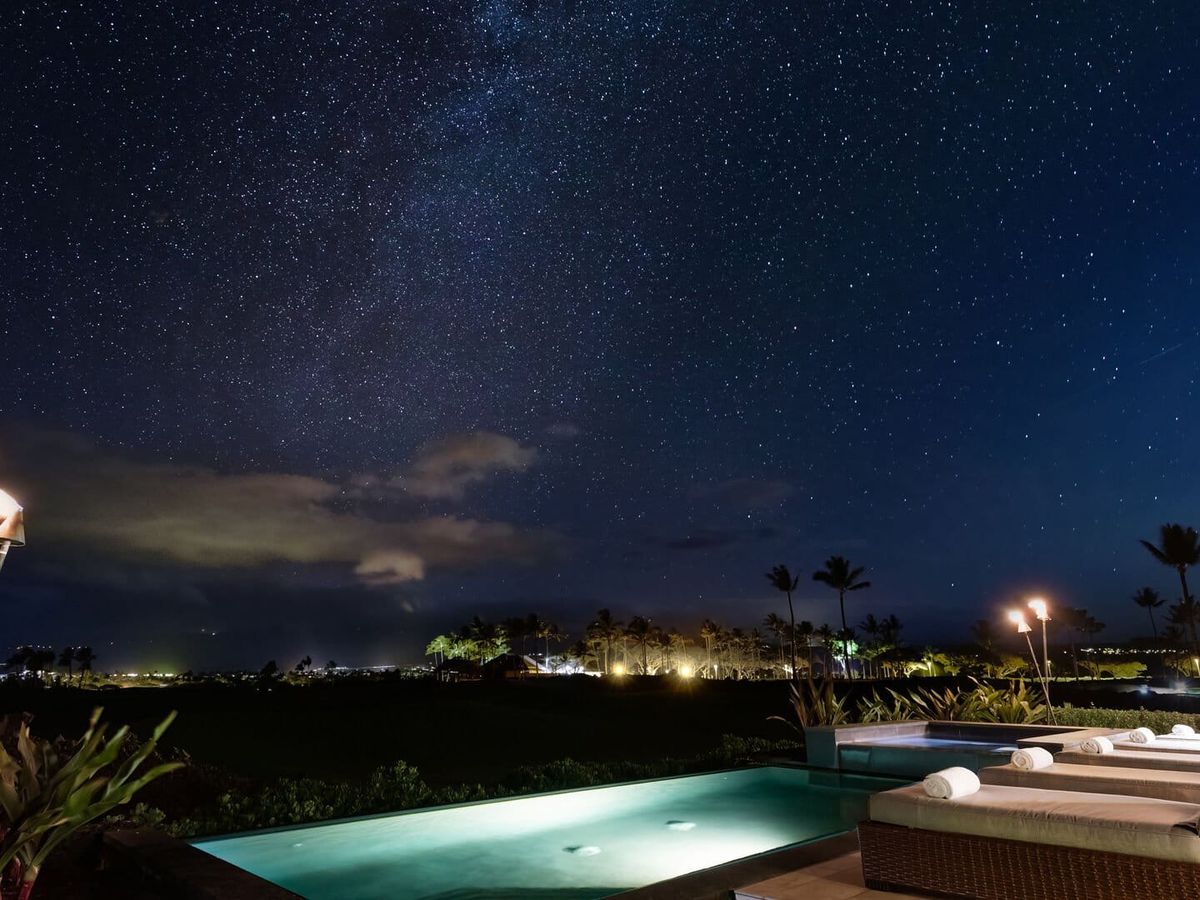 Elegant Escape features a glowing private pool and lounge chairs beneath a clear, star-filled Hawaiian sky. The peaceful outdoor setting gives guests a beautiful place to unwind and enjoy Hawaii after dark.