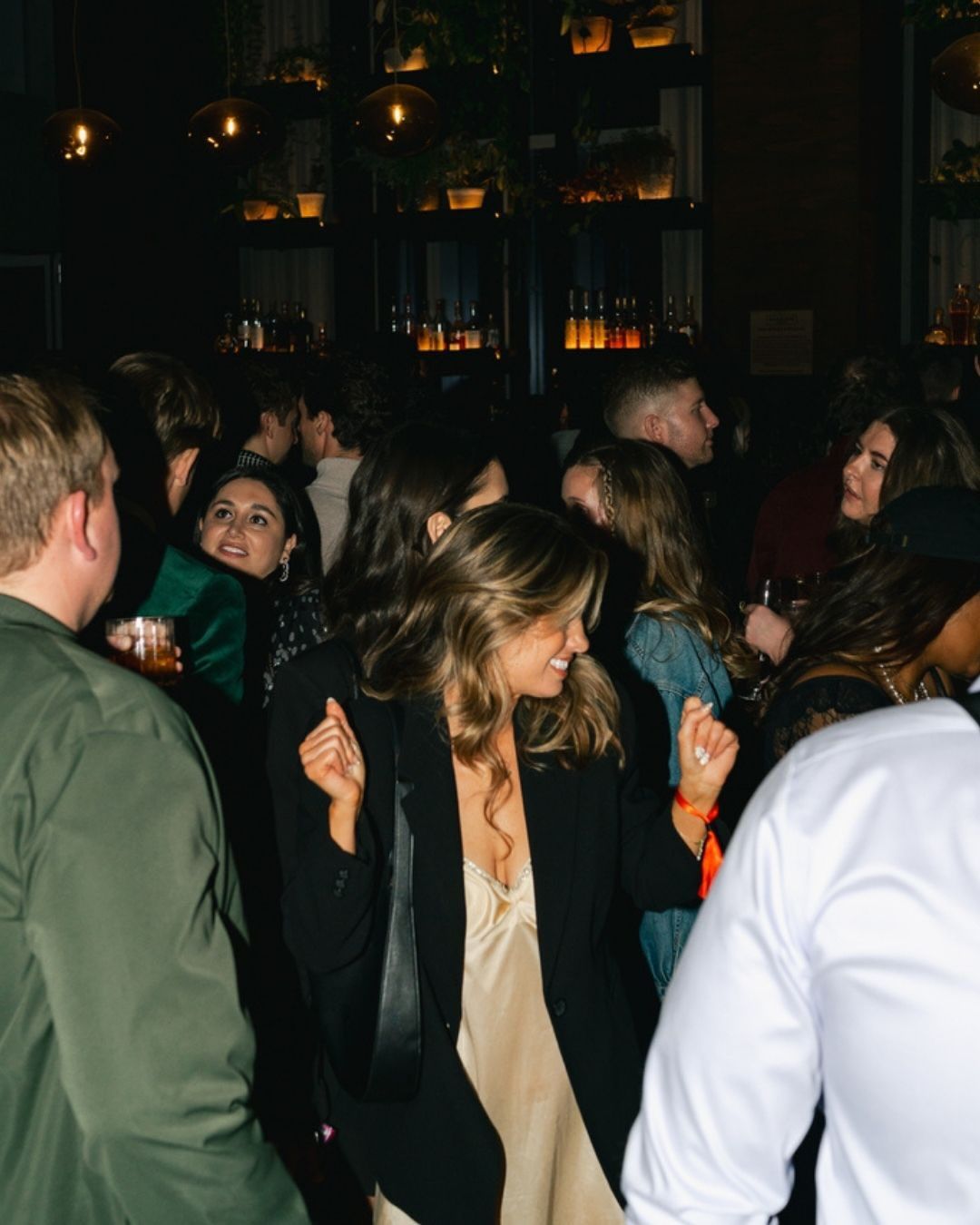 A lively rooftop party at Harriet's Rooftop Nashville with guests dressed up, chatting, and enjoying drinks under warm city lights. This stylish venue is popular for nightlife, social events, and skyline views in downtown Nashville.