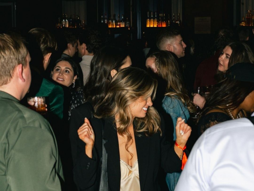 A lively rooftop party at Harriet's Rooftop Nashville with guests dressed up, chatting, and enjoying drinks under warm city lights. This stylish venue is popular for nightlife, social events, and skyline views in downtown Nashville.