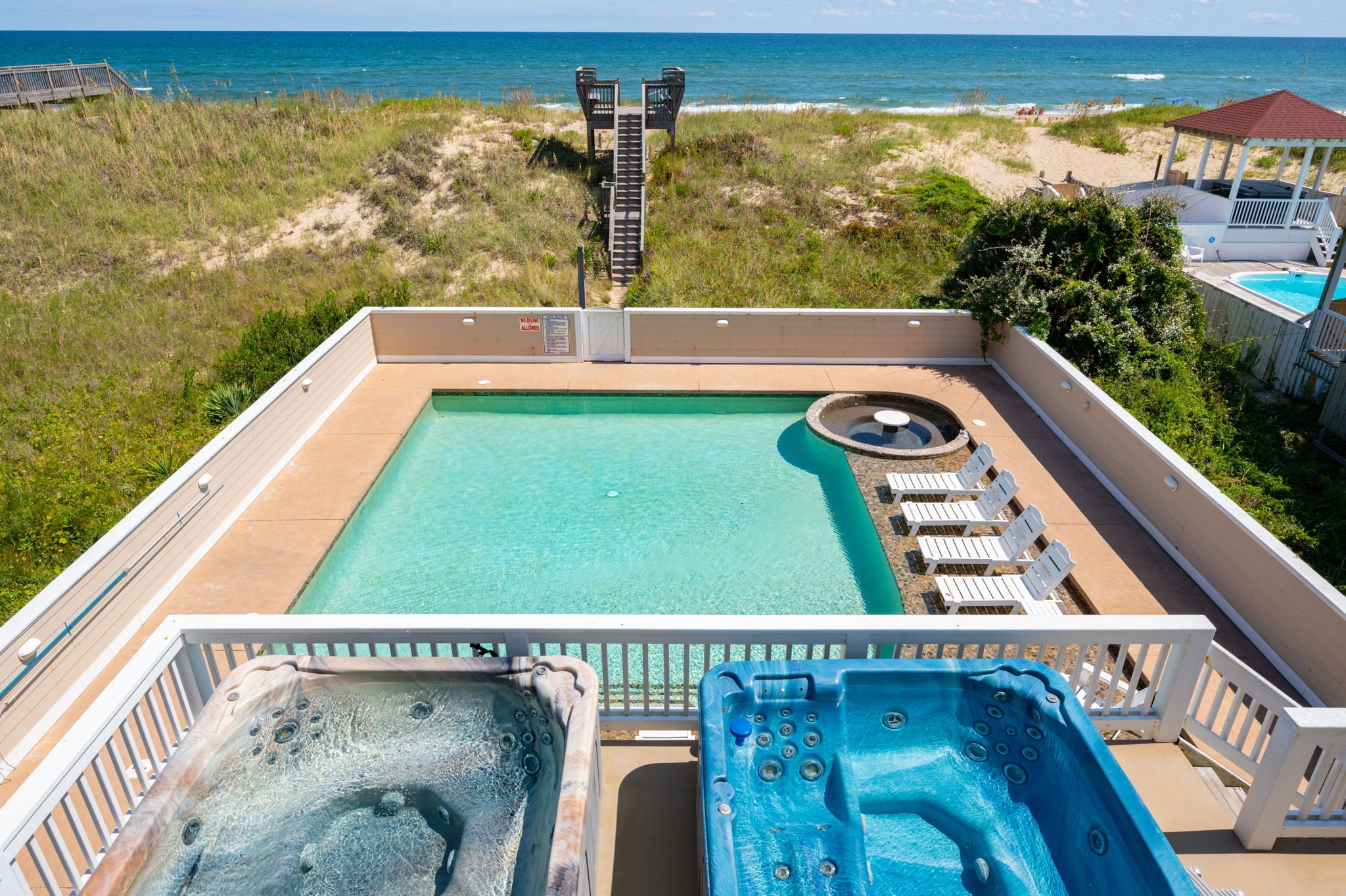 Two private hot tubs side by side overlooking private pool and wooden steps leading to beach access