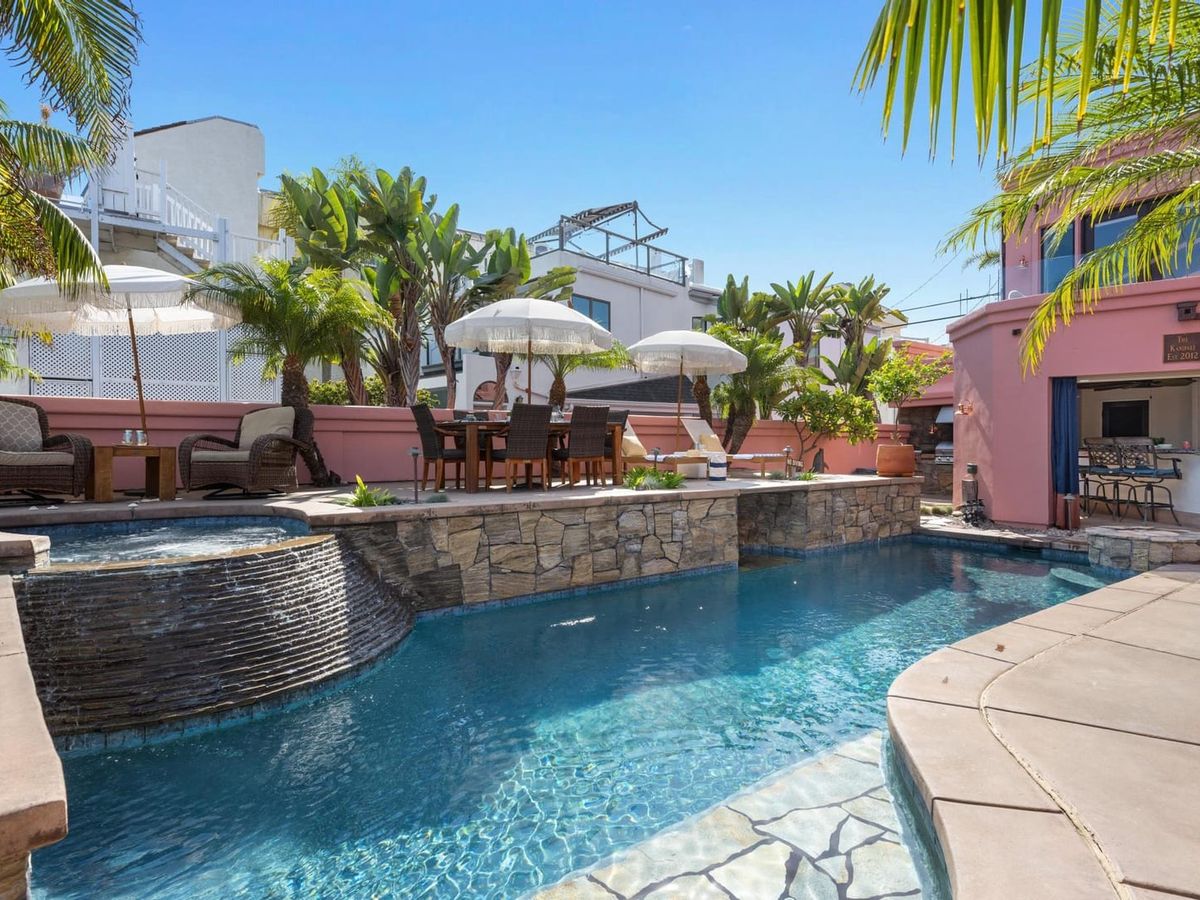 This tropical backyard oasis in Mission Bay features a sparkling stone-edged pool, shaded loungers, and lush palm trees. Kanipali is ideal for family cookouts, lazy pool days, and sunset cocktails in style.