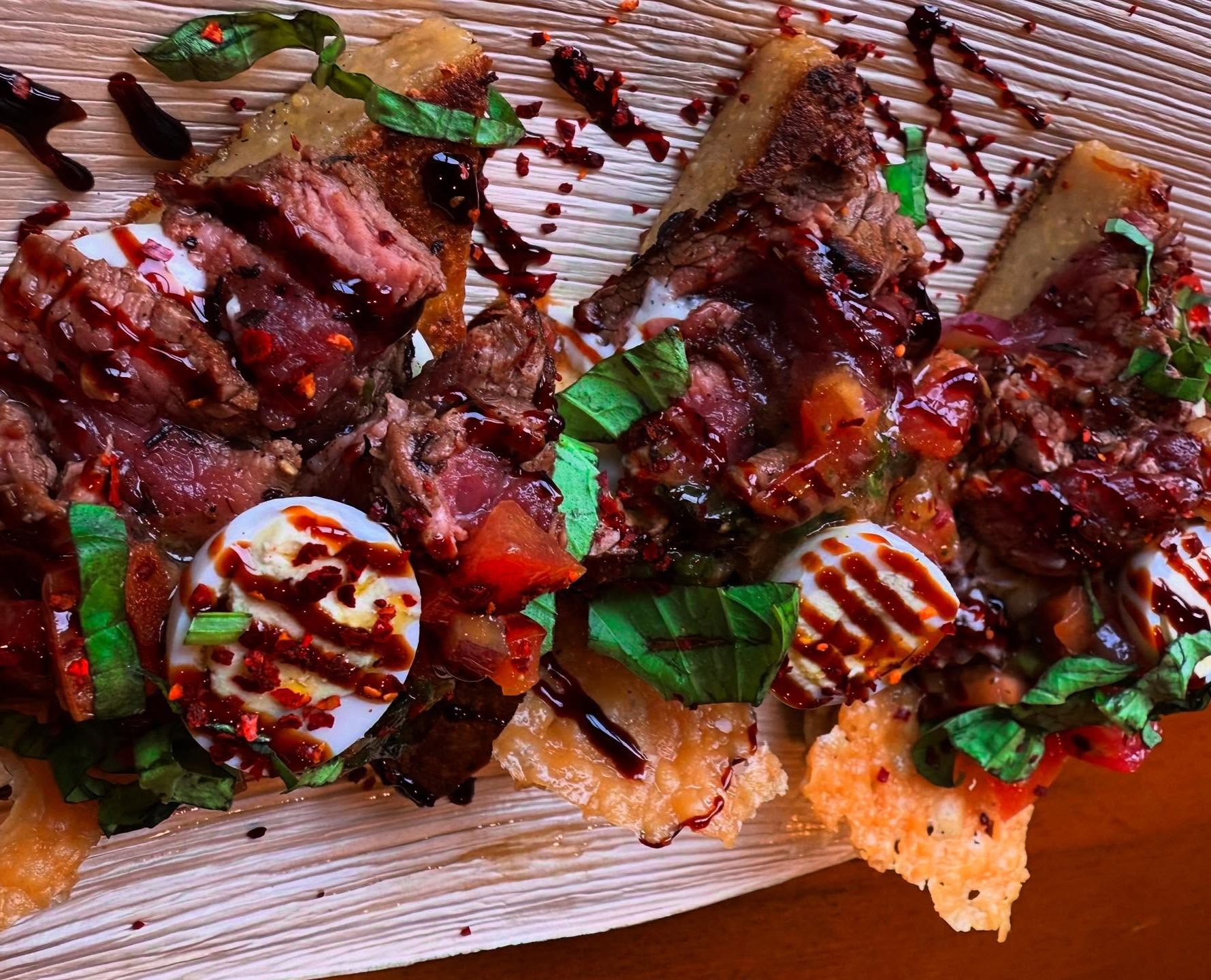 A fresh gourmet sandwich stacked with tomatoes, greens, and creamy sauce on toasted bread. The sandwich is cut in half and served in a bowl, showing colorful layers of ingredients. This hearty café-style sandwich is a popular lunch option at Highlands Tavern & Eatery.
