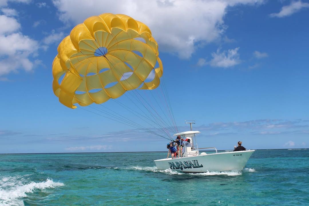 A bright yellow parasail lifts adventure seekers high above the sparkling blue ocean, towed by a speedboat below. With the wind in their faces and panoramic island views, it’s an unforgettable way to see the Bahamas from above.