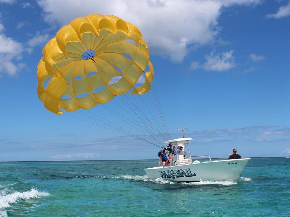 A bright yellow parasail lifts adventure seekers high above the sparkling blue ocean, towed by a speedboat below. With the wind in their faces and panoramic island views, it’s an unforgettable way to see the Bahamas from above.