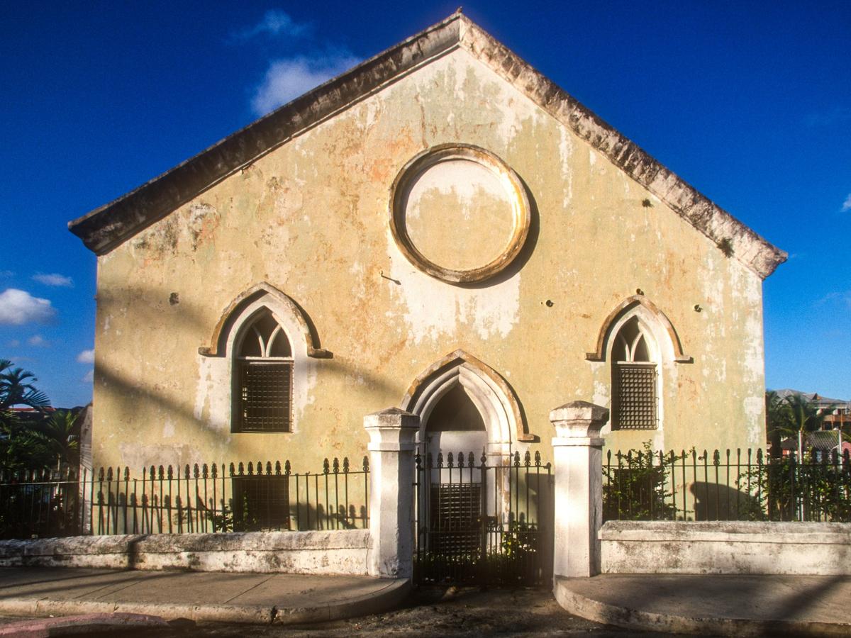 Old, historic building in Nassau Bahamas with fence guarding it and palm trees beside it