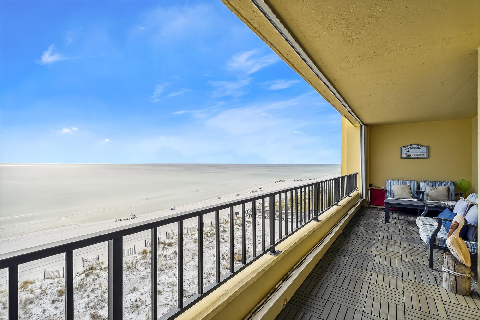 A beachfront condo with panoramic views of white sand and turquoise water. The cozy balcony seating invites guests to unwind and enjoy the gentle sound of the waves in Destin.