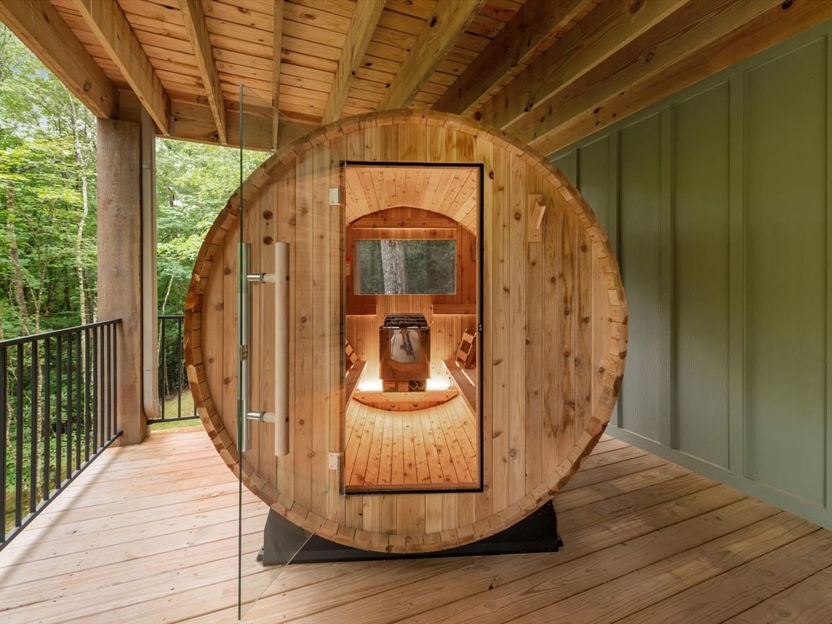 Unique barrel sauna open on balcony surrounded by trees