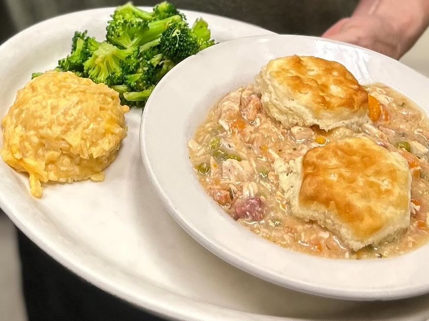 Comfort food at its fines this plate features a hearty chicken stew topped with fluffy biscuits, served with cheesy hash brown casserole and fresh broccoli. A cozy Southern-style meal that hits all the right notes.
