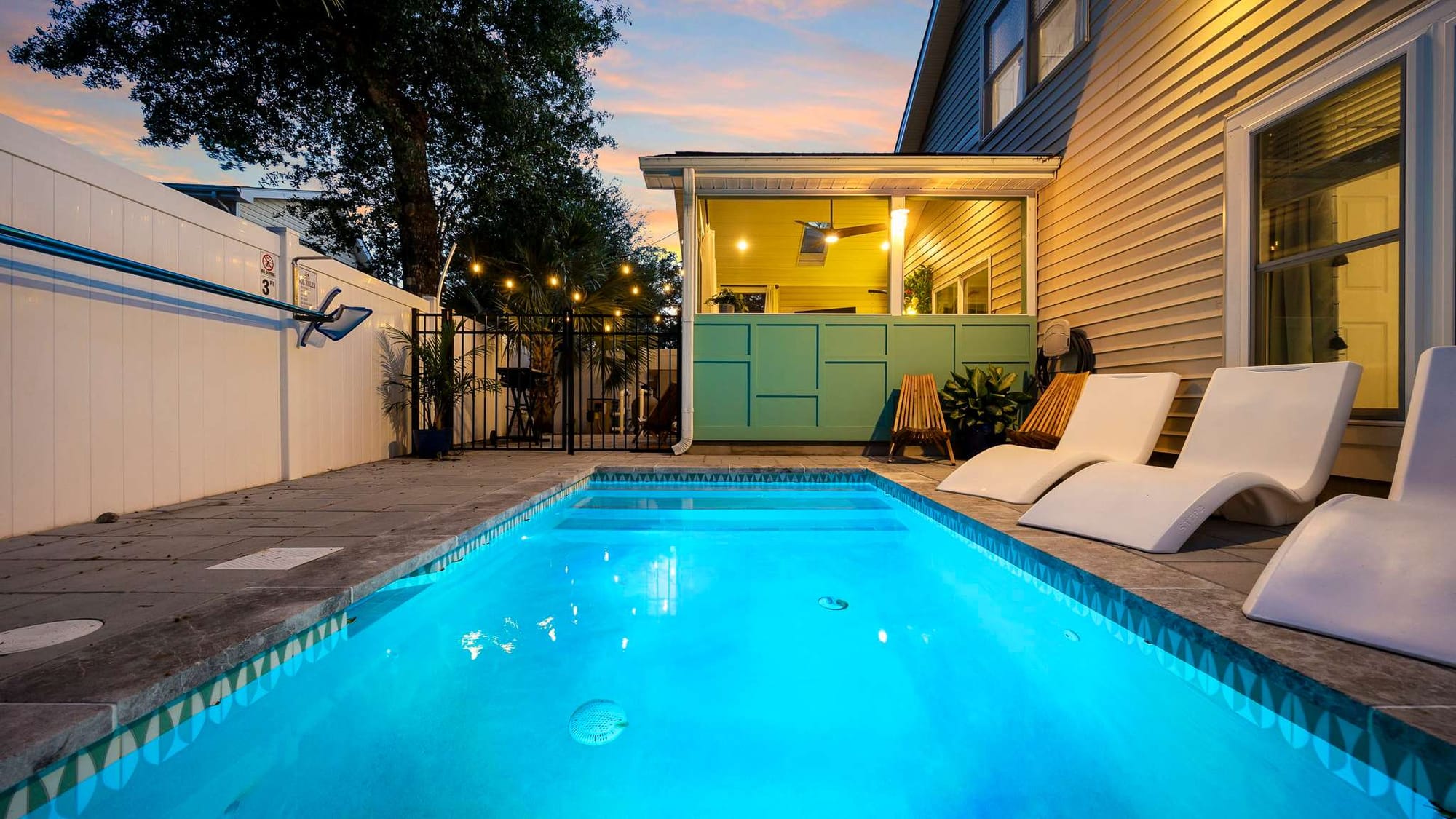Bright and inviting, this modern home features a sleek blue pool surrounded by lounge chairs and cozy seating. Perfect for families, it’s designed for lazy afternoons in the sun and relaxed nights under string lights.