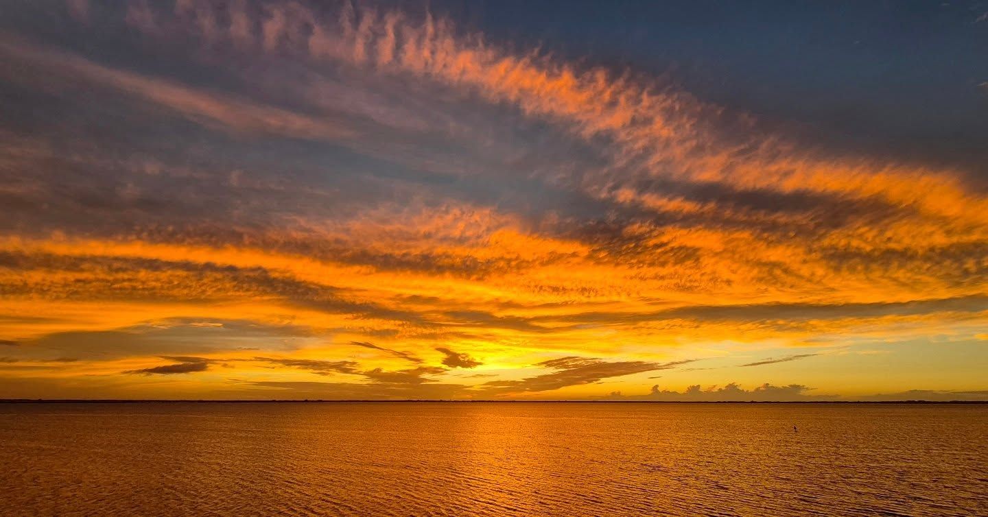 A breathtaking sunset lights up the sky in shades of gold and orange over calm ocean waters. This view reflects the warm, welcoming spirit of Cocoa Beach, where every evening ends in color and calm.