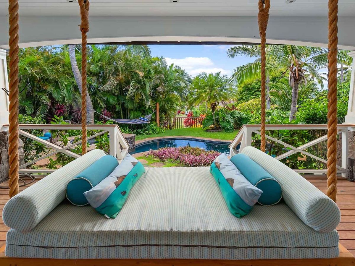 Swinging day bed overlooking private pool, hammock, and garden in backyard of Kauai cottage