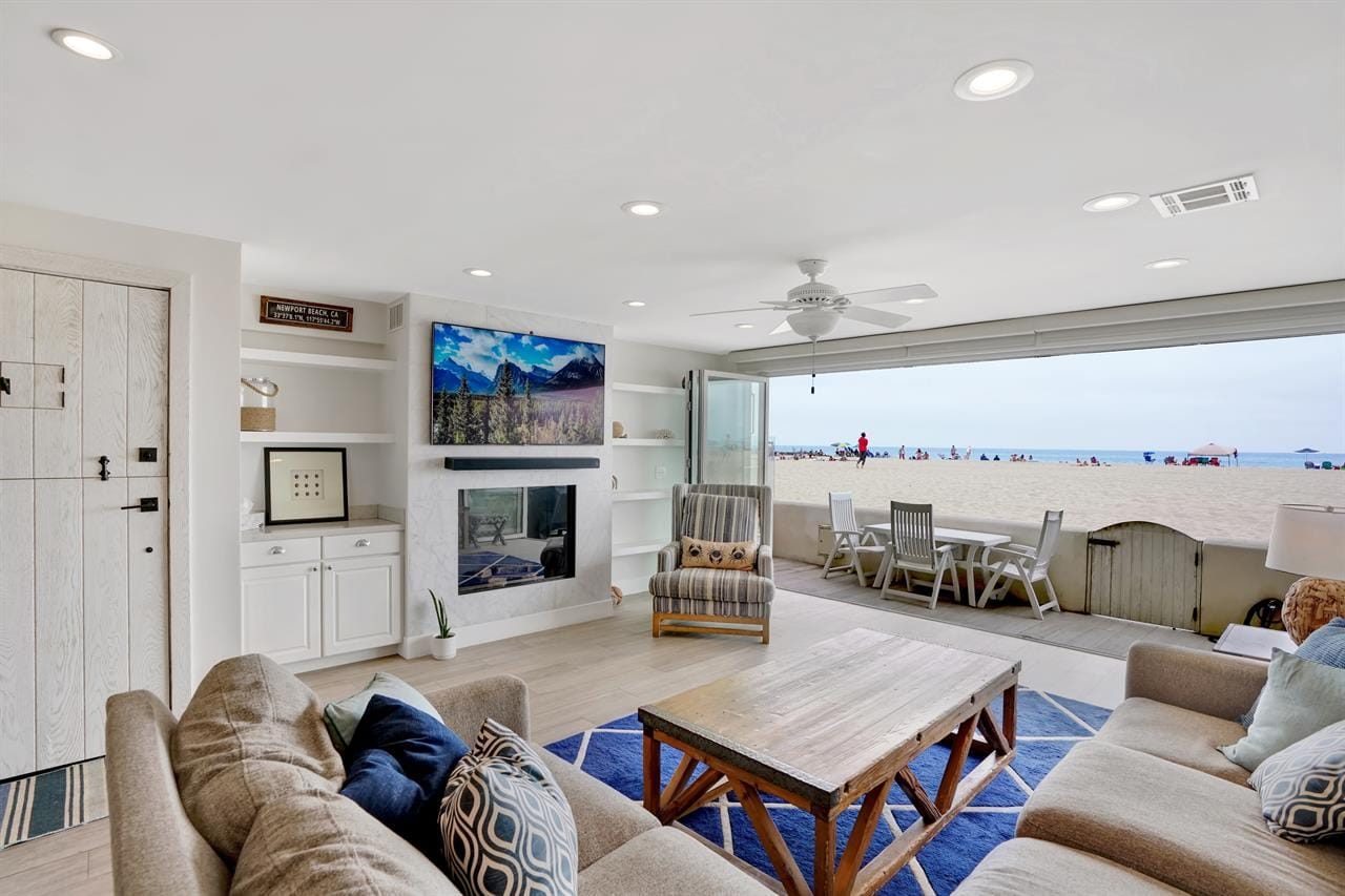 This cozy beach house living room opens straight onto the sand, giving you a clear view of the ocean from the couch. The wide glass doors let in tons of natural light, making the space feel bright and relaxed. It’s the kind of spot where you can watch the waves while hanging out with friends or family.