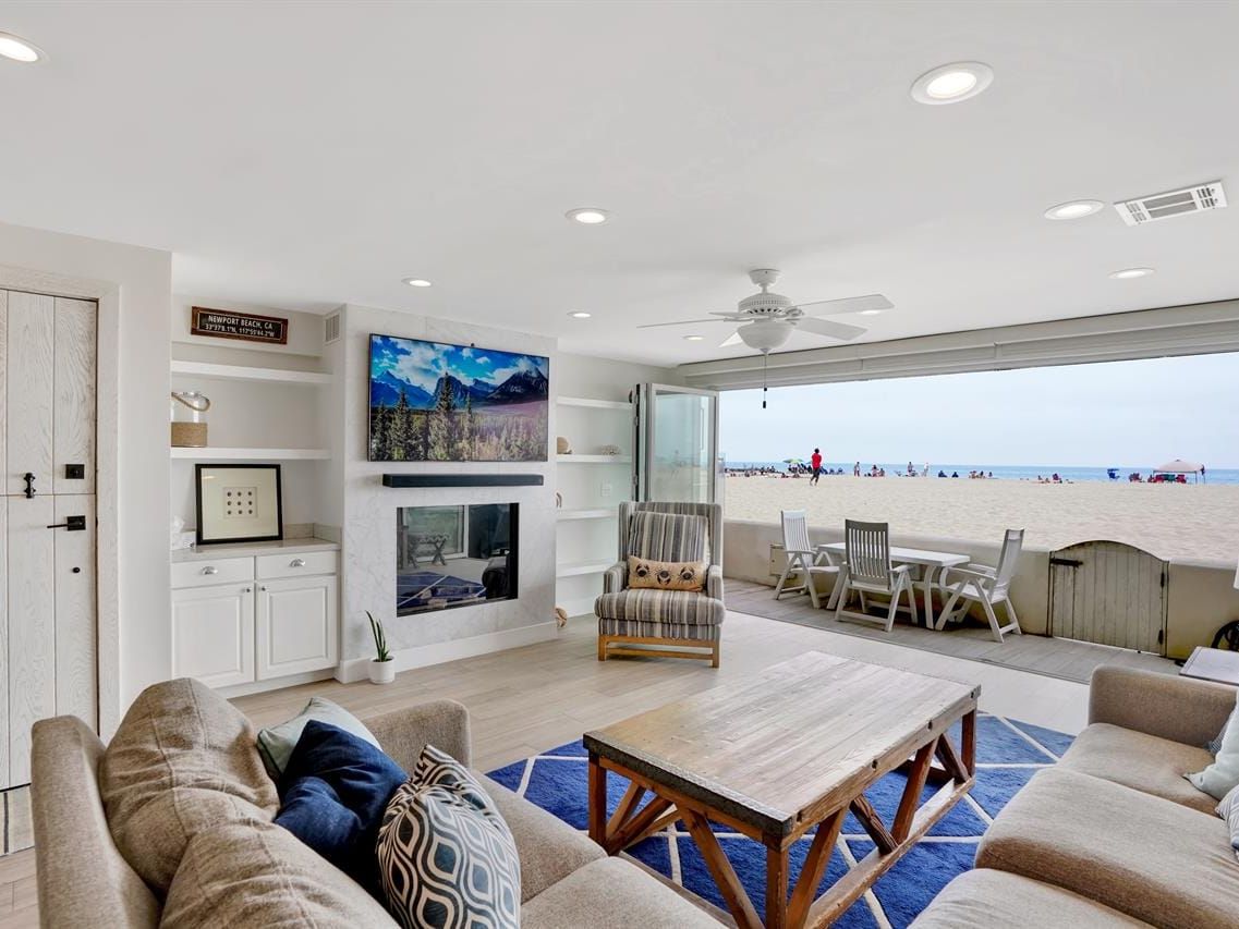 This cozy beach house living room opens straight onto the sand, giving you a clear view of the ocean from the couch. The wide glass doors let in tons of natural light, making the space feel bright and relaxed. It’s the kind of spot where you can watch the waves while hanging out with friends or family.