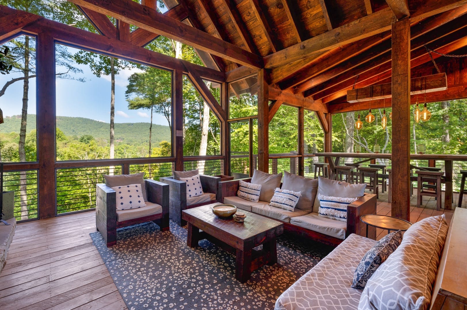 Copperline Lodge offers a spacious screened-in deck with mountain views, rustic wood beams, and comfortable seating. This inviting outdoor space is perfect for group gatherings and enjoying the fresh Blue