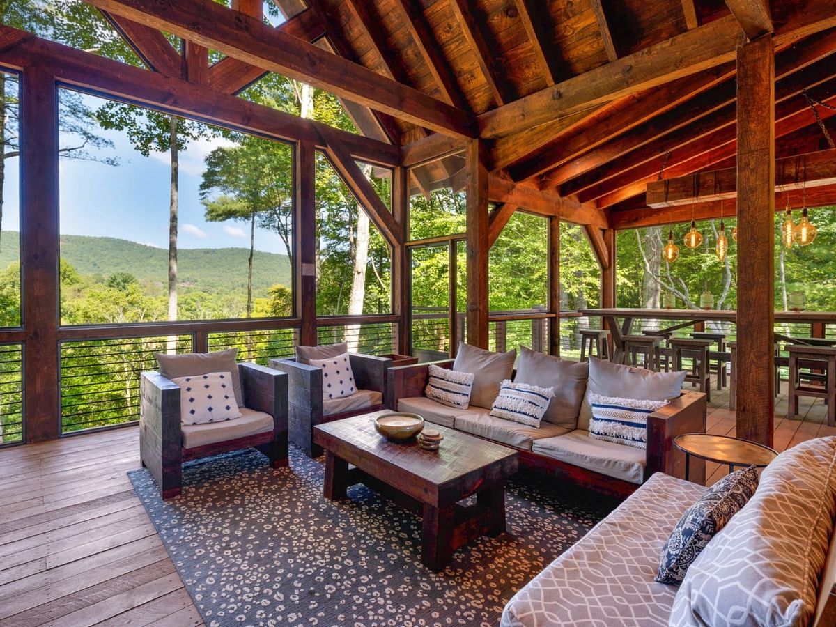 Copperline Lodge offers a spacious screened-in deck with mountain views, rustic wood beams, and comfortable seating. This inviting outdoor space is perfect for group gatherings and enjoying the fresh Blue