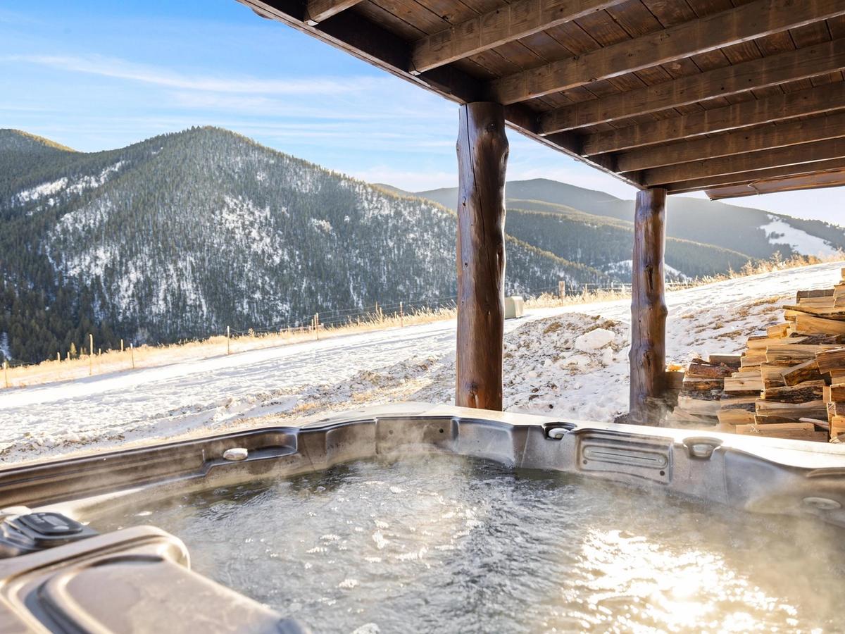 Private hot tub with snow on the ground and hills in the backgground