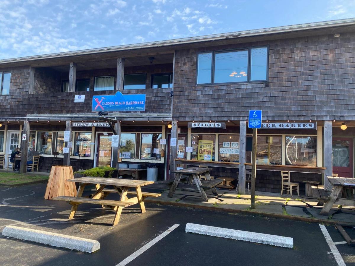 The rustic exterior of Screw and Brew at Cannon Beach Hardware & Public House, featuring picnic tables and a laid-back coastal vibe. This local favorite is a great stop for craft drinks and casual bites after a day exploring Cannon Beach.