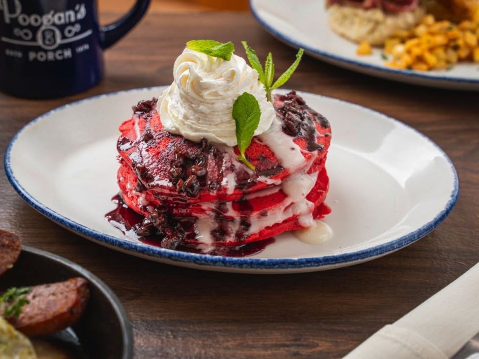 Red velvet pancakes drizzled with cream cheese glaze and berry sauce, topped with whipped cream. A sweet and cozy brunch favorite.