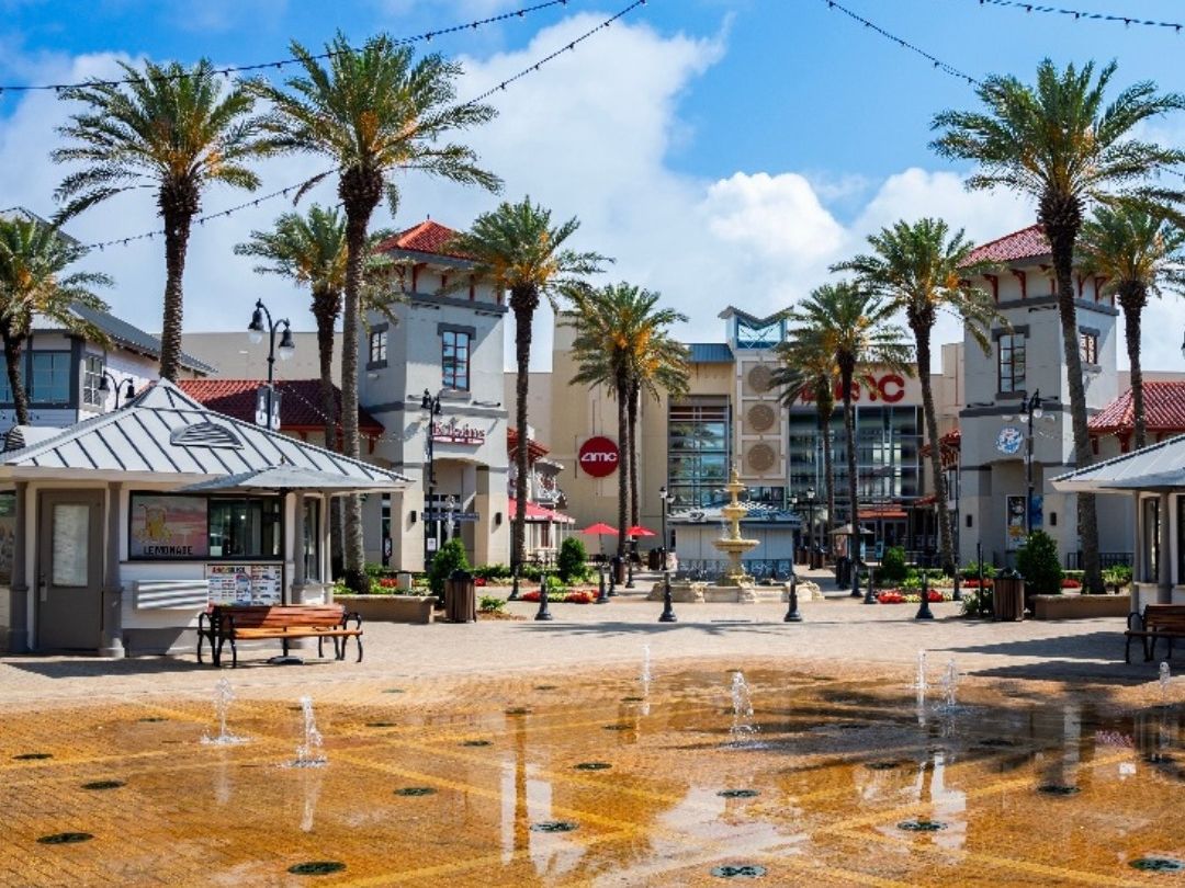 The open-air shopping plaza at Destin Commons, featuring palm trees, colorful storefronts, fountains, and a lively family-friendly atmosphere. A top destination for shopping and dining in Destin