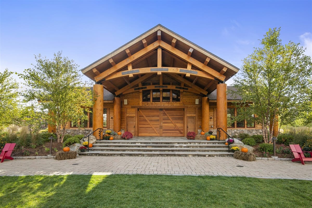 Alpine Elegance 47C features a grand timber entrance with natural wood beams, stone details, and landscaped grounds. The lodge-style design creates a warm welcome for a relaxing stay in Stowe, Vermont.