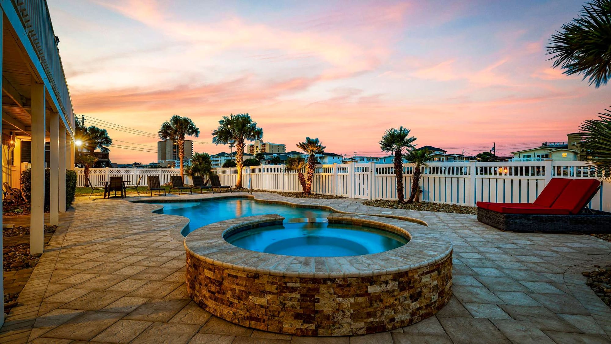 Private outdoor pool and hot tub glow beautifully at sunset, creating a relaxing backyard retreat. Lounge chairs and palm trees add a tropical feel, perfect for evening swims after a beach day.