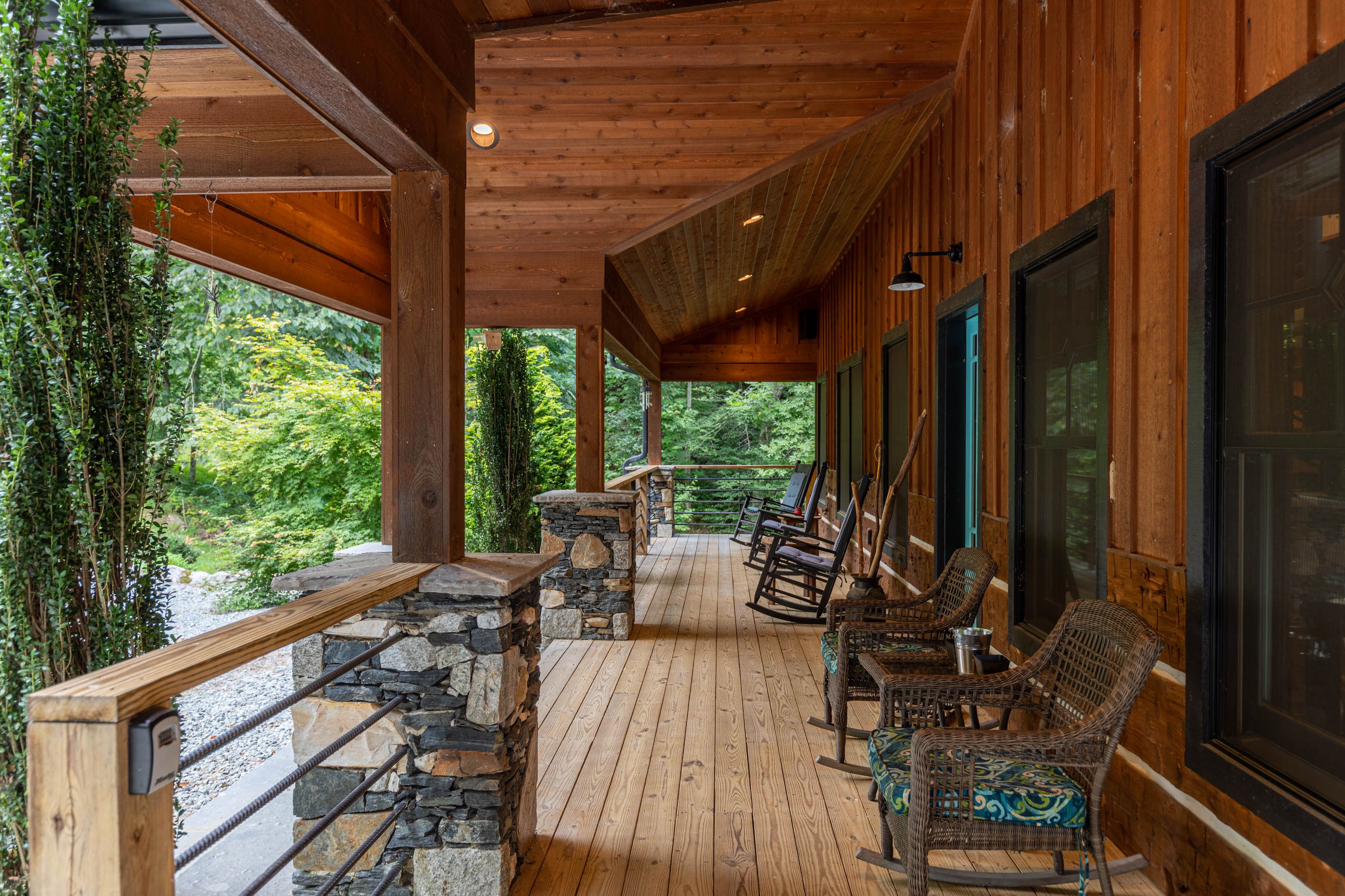 Balcony that overlooks mountainous woods and trees with chairs on porch