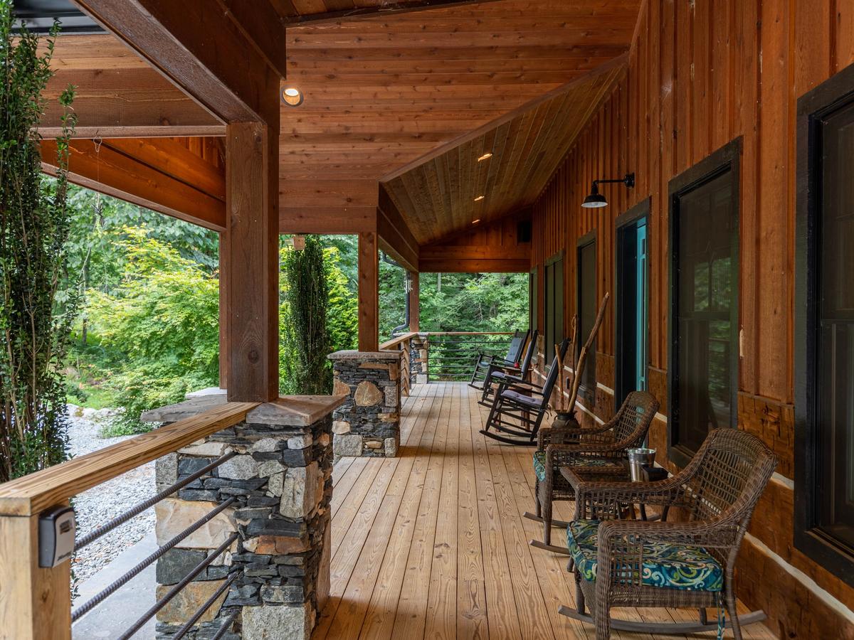 Balcony that overlooks mountainous woods and trees with chairs on porch