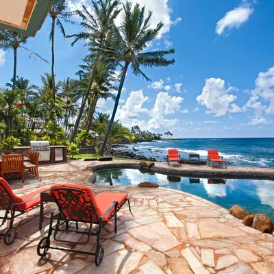 Oceanfront patio with a stone deck, cozy lounge chairs, and a natural pool.