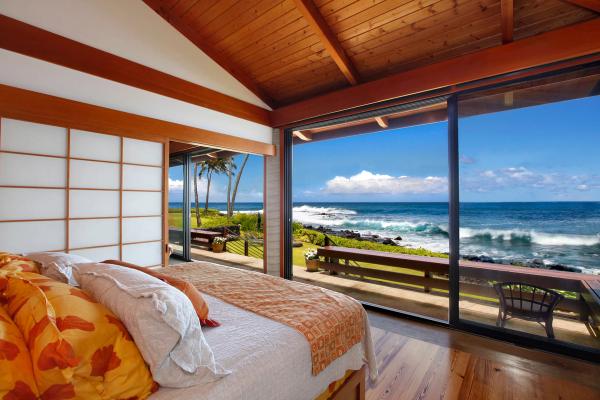 Cozy bed with vibrant orange bedding, wooden ceiling beams, and minimalist decor