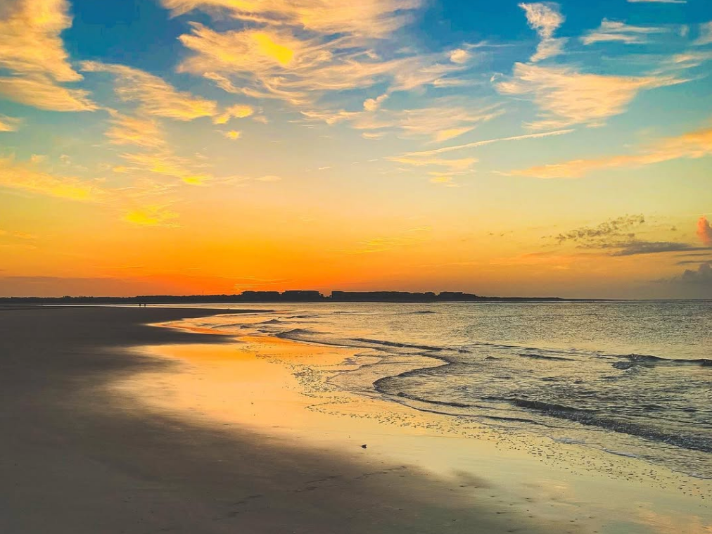 orange and blue sunset with beach sands and water gently on the sand
