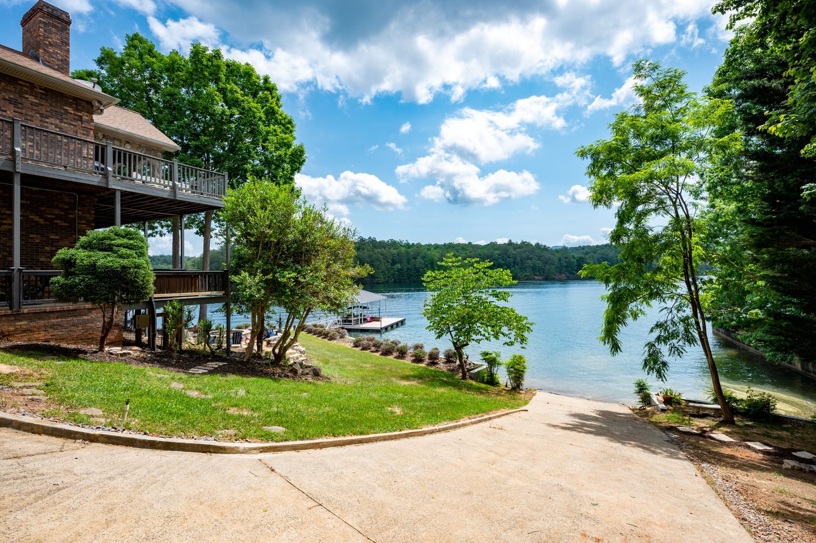 Aerial view of a wooded shoreline with private docks and boats resting on calm green water. The scene captures the charm of lakefront living in the Blue Ridge area, where adventure meets quiet relaxation